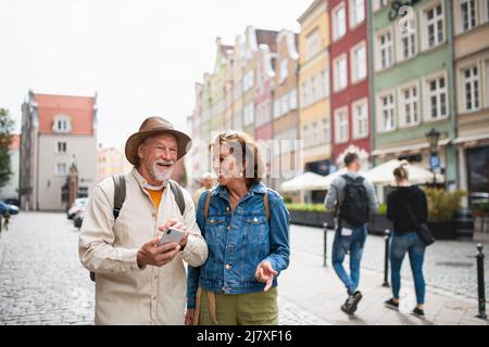 Portrait de heureux couples de personnes âgées en utilisant un smartphone en plein air dans la ville historique Banque D'Images