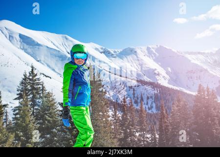 Un garçon en tenue de ski ou de snowboard se trouve au-dessus de la montagne enneigée Banque D'Images