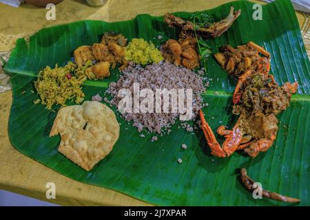 repas traditionnel de pittu de jaffna servi sur une feuille de banane entourée de cari de crabe de jaffna, de poisson local, de curry de crevettes, de pommes de terre de légumes et de papopadom Banque D'Images