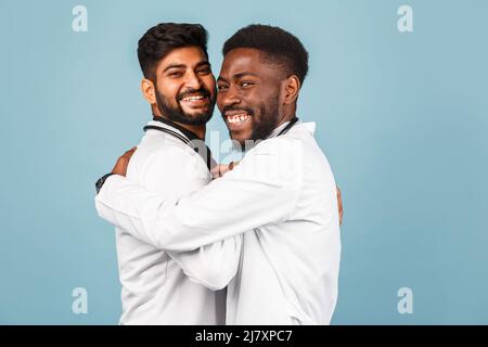 portrait de przloseup d'un professionnel de la santé intellectuel avec un laque blanc discutant des résultats avec un jeune médecin sur fond bleu Banque D'Images