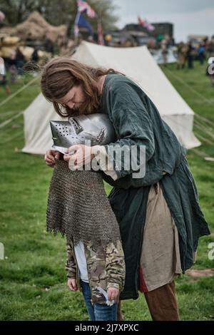 Un guerrier viking aide un garçon à retirer le casque d'un chevalier lors de l'événement No Man's Land au Bodrhyddan Hall, au pays de Galles Banque D'Images