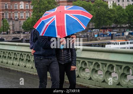 Londres, Royaume-Uni, 11 mai 2022. Les piétons qui se rancune avec des parasols sur le pont de Westminster pendant les averses de pluie. Le temps devrait s'améliorer et des températures plus élevées sont prévues dans les jours à venir à Londres et sud-est de l'Angleterre crédit. amer ghazzal/Alamy Live News Banque D'Images