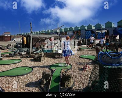 Femme dans une robe colorée appréciant jouer au mini-golf à Hove Lagoon Banque D'Images