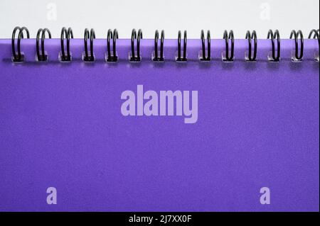 Fait partie d'un cahier wirebond (ou à spirale) avec couvercle en plastique violet translucide sur fond blanc. Banque D'Images