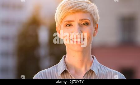 Portrait à l'extérieur femelle heureux visage souriant naturel maquillage tête caucasienne avec cheveux courts mature 40s femme d'affaires debout posant à l'extérieur Banque D'Images