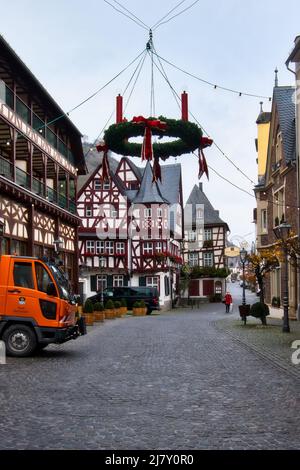 Couronne de Noël verte suspendue sur une rue pavée près de Altes Haus avec une femme portant un masque de marche pendant le confinement de la COVID à Bacharach, Germa Banque D'Images