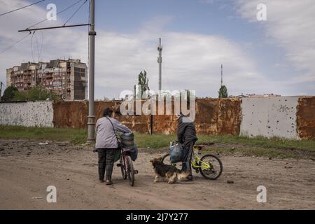 Kharkiv, Ukraine. 11th mai 2022. Deux personnes marchent leurs vélos près d'un mur en pots avec des éclats de shrapnel russes dans les parties nord de Kharkiv, Ukraine, mercredi, 11 mai 2022. Mardi, les États-Unis et leurs alliés européens ont accusé la Russie d'avoir lancé une cyber-attaque une heure avant l'invasion de l'Ukraine par le Kremlin en février, qui visait une société de communications américaine opérant à Kiev, causant des dégâts sur l'ensemble du continent. Photo de Ken Cedeno/UPI crédit: UPI/Alay Live News Banque D'Images