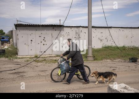 Kharkiv, Ukraine. 11th mai 2022. Un homme marche son vélo près d'un mur en pots avec un shrapnel de Russie shelling dans les parties nord de Kharkiv, Ukraine, le mercredi 11 mai 2022. Mardi, les États-Unis et leurs alliés européens ont accusé la Russie d'avoir lancé une cyber-attaque une heure avant l'invasion de l'Ukraine par le Kremlin en février, qui visait une société de communications américaine opérant à Kiev, causant des dégâts sur l'ensemble du continent. Photo de Ken Cedeno/UPI crédit: UPI/Alay Live News Banque D'Images