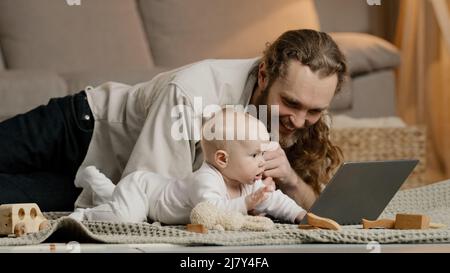 Adulte caucasien père seul barbu avec bébé nouveau-né faire un appel vidéo à la mère ou à des parents papa à l'intérieur avec bébé se faisant des mains Banque D'Images