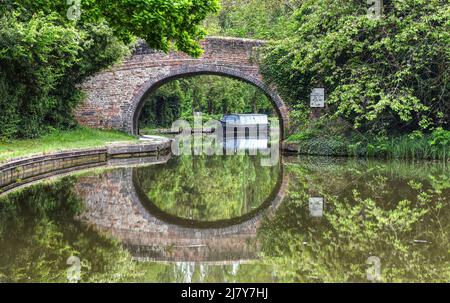 Un vieux pont se reflète dans les eaux parfaitement fixes du Canal de la Grande Union à Milton Keynes Banque D'Images