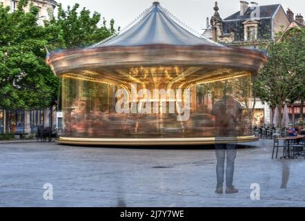 Un tour de manège tourne autour dans cette exposition multiple prise dans un carré dans le centre de Troyes, France Banque D'Images