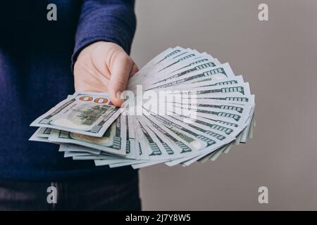L'homme tient un fan de billets de cent dollars. Banque D'Images