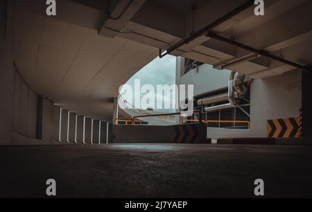 Vue en perspective de la rampe en forme de courbe sur le bâtiment supérieur pour les parkings intérieurs en spirale tour avec des canaux lumineux depuis le mur de ciment. Copier l'espace Banque D'Images