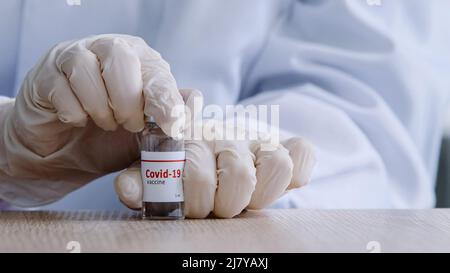 Gros plan les mains des femmes de l'infirmière médecin travailleur médical tenant une bouteille de vaccin Covid 19 bocal ouvert de coronavirus médicament liquide antibiotique médecine Banque D'Images