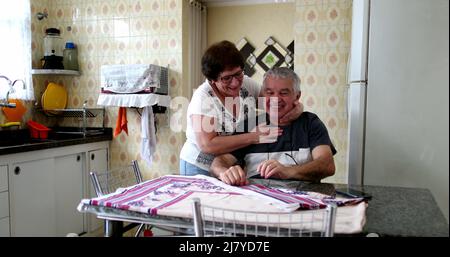 Joyeux senior commémorant les bonnes nouvelles sur le téléphone portable. Couple marié à la cuisine maison célébrant Banque D'Images