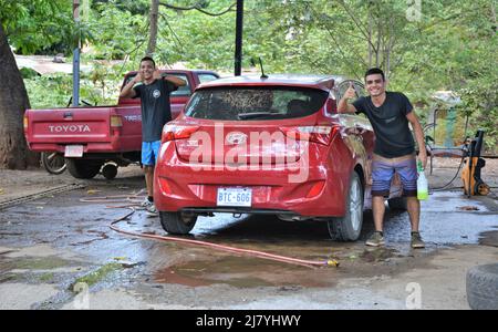 Les hommes poussant le bateau dans le surf sur la plage du Costa Rica Banque D'Images