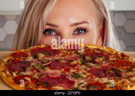 femme ouvrir des fours et couper des pizzas avec des tomates, des olives, des champignons et des saucisses au fromage Banque D'Images