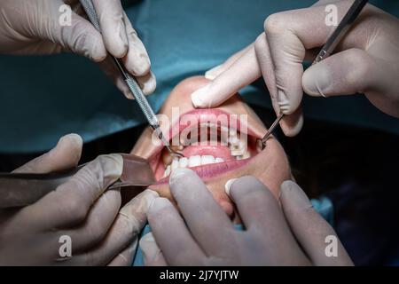 Dentiste examinant la bouche d'un patient avec différents outils dans la salle d'opération avant une chirurgie Banque D'Images