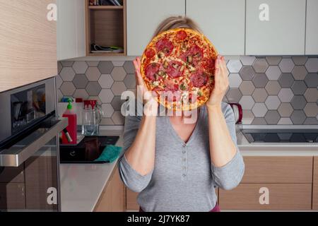 femme ouvrir des fours et couper des pizzas avec des tomates, des olives, des champignons et des saucisses au fromage Banque D'Images