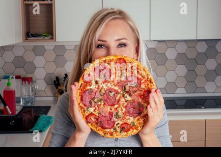 femme ouvrir des fours et couper des pizzas avec des tomates, des olives, des champignons et des saucisses au fromage Banque D'Images