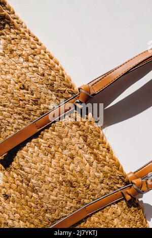 Sac de plage en paille élégant sur fond blanc, vue du dessus. Accessoires d'été, lumière naturelle Banque D'Images