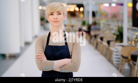 Adulte adulte adulte âge moyen 40s femme dame restaurant café travailleur regardant la caméra posant croisant les bras femme serveuse vendeuse en tablier debout à Banque D'Images