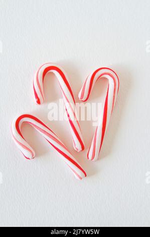 Trois Cannes de bonbons rayées sur un fond blanc vertical, photo prise du dessus. Banque D'Images