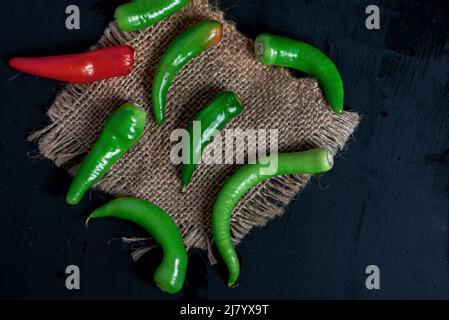 Piments verts sur une nappe hessienne sur une table en bois noir, gros plan, photographie de la vie Banque D'Images