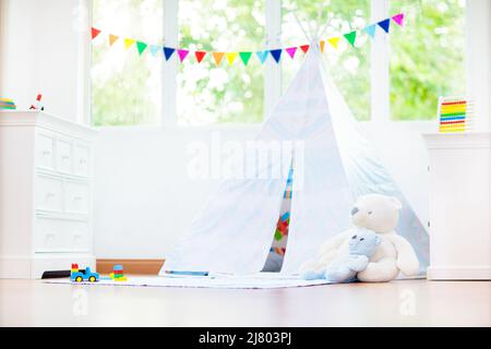 Chambre pour enfants avec tente à tipi. Les enfants jouent dans une chambre blanche ensoleillée. Intérieur lumineux et confortable pour la garderie ou la salle de jeux. Banque D'Images