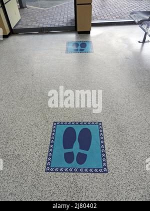 CHORLEY. LANCASHIRE. ANGLETERRE. 04-19-22. Marqueurs sociaux de distance sur le plancher de la gare routière pour faciliter le contrôle de file d'attente pour l'embarquement en bus. Banque D'Images