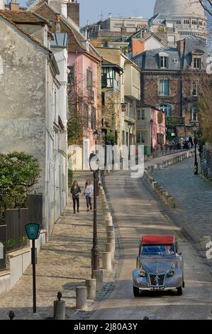 A 1950s Citroën convertible 2CV en voiture de la Maison Rose, rue de l’Abreuvoir, vers la rue Girardon et le buste de Dalida à Monxe. Banque D'Images