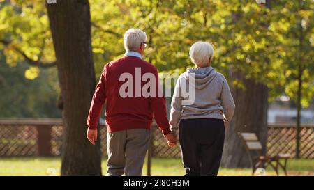 Photo en arrière d'un couple retraité senior qui passe son temps libre en marchant dans un parc voisin en automne. Amour véritable et relations durables. Photo de haute qualité Banque D'Images