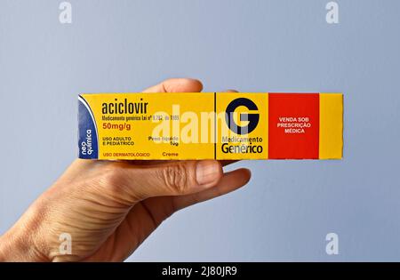 RIO DE JANEIRO, BRÉSIL - 10 MAI 2022 : main tenant une boîte de crème d'Acyclovir, médicament utilisé pour le traitement de l'herpès. Antiviral puissant. Banque D'Images