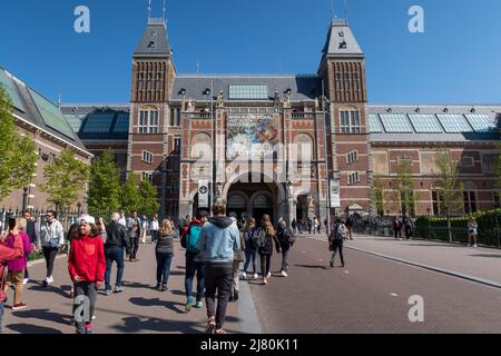 Foules de touristes marchant vers le bâtiment historique Rijksmuseum à Amsterdam par une journée ensoleillée Banque D'Images