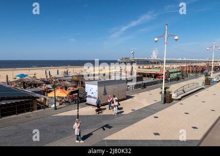 Journée ensoleillée à la plage de Scheveningen à la Haye, aux pays-Bas, avec des gens marchant le long de la promenade et la jetée en arrière-plan Banque D'Images