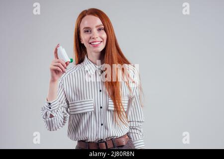 redhead femme d'affaires étudiant de tourisme dans une chemise rayée ayant l'asthme en utilisant l'inhalateur d'asthme pour être sain blanc fond studio Banque D'Images