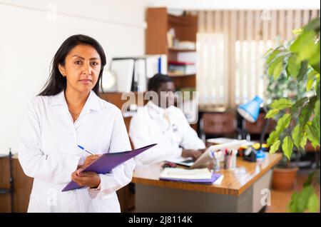 Femme polie médecin remplissant le formulaire médical à la planchette à pince Banque D'Images