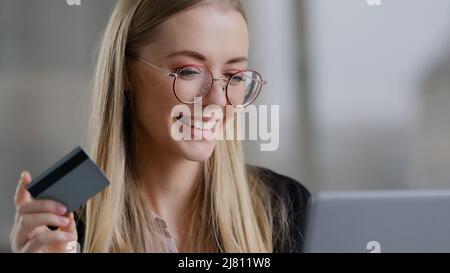 Souriante femme d'affaires caucasienne shopping en ligne en utilisant l'ordinateur portable payer avec la carte de crédit acheter commande réservation à distance net. Bonne 30s femme avec Banque D'Images