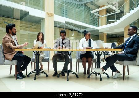 un groupe de succès afro-américains, européens, arabe et coréen homme d'affaires et femme d'affaires travaillant dans le bureau avec de grandes fenêtres en verre Banque D'Images