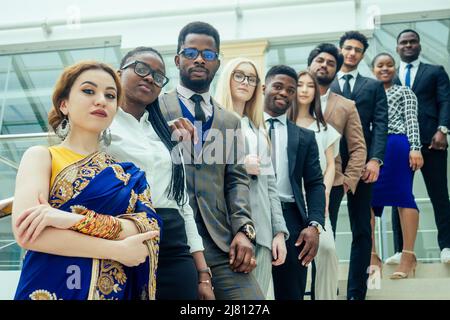 un groupe d'afro-américains, d'européens, d'hommes d'affaires et de femmes d'affaires arabes et coréens et indiens qui travaillent dans le bureau avec un grand verre Banque D'Images