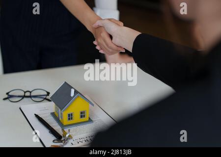 Le client reçoit une excellente affaire après avoir signé un contrat pour acheter une maison. Le courtier et le client se bousculer après avoir fait une bonne affaire. Immobilier Banque D'Images