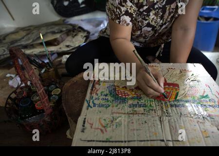 Femme colorant une marionnette en cuir au musée Ban Nang Talung (marionnettes à ombre), un atelier appartient à l'artiste Suchart Subin à Nakhon si Thammarat, Thaïlande. Banque D'Images