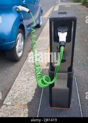 Un point de charge de véhicule électrique escamotable est utilisé pour charger une voiture électrique bleue. Ce point de charge d'Urban Electric se rétracte dans le pavé lorsqu'il n'est pas utilisé. Banque D'Images