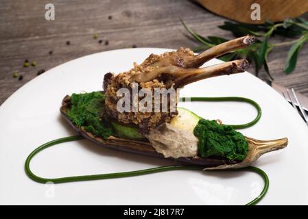 Carré d'agneau en pâte de noix avec légumes cuits au four. Pâte d'épinards et aubergine cuite au four. Aliments moléculaires. Banque D'Images