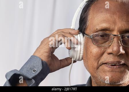 Gros plan d'un vieil Indien aime la musique avec un casque blanc Banque D'Images