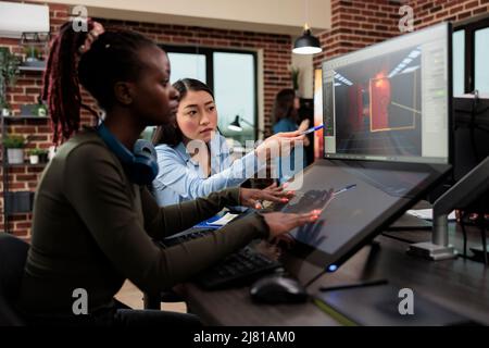 Travailleurs de l'industrie du divertissement interactif numérique travaillant avec CGI. Développement de jeux agences créatives artistes conversant sur la conception de niveau et 3D actifs tout en étant assis dans un espace de travail de bureau. Banque D'Images