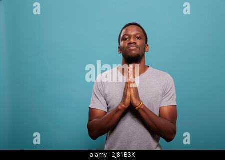 Homme religieux tenant la main dans le signe de prière pour adorer Dieu, ayant foi en Jésus et le christianisme. Personne spirituelle utilisant l'évangile catholique de la religion pour prier pour la pureté et l'âme pacifique. Banque D'Images