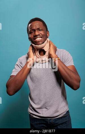 Déçu adulte portant col de l'utérus pour guérir les blessures physiques après accident d'os entorses. Jeune homme avec de la mousse de cou souffrant de vertèbres fracturées, souffrant de douleur à la réadaptation. Banque D'Images