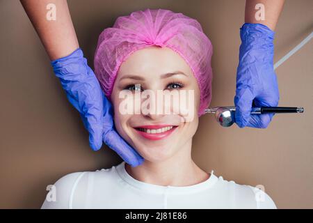 femme recevant un massage facial avec oxy air spray .oxygénothérapie dans le salon de spa.gros plan sur le visage de la joue du patient Banque D'Images