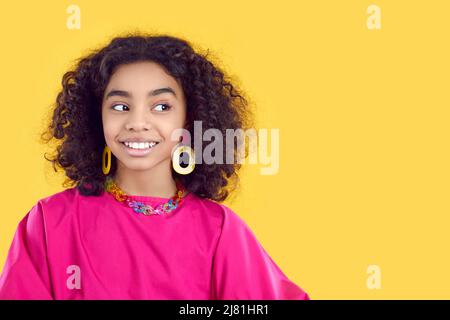 Belle fille africaine dans la tenue tendance regarde l'espace de copie sur fond jaune Banque D'Images